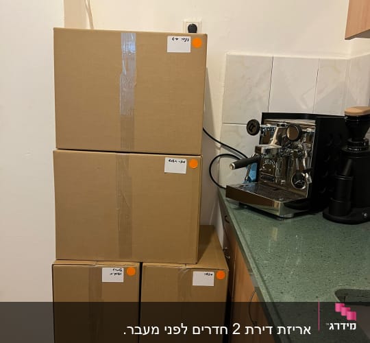 שישה קרטונים מסומנים במדבקות כתומות על משטח ירוק